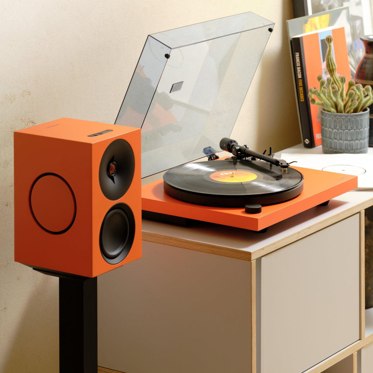 Cambridge Audio Spira Belt Drive Turntable, Orange, lifestyle, on a shelf unit beside a matching Orange L/R active speaker