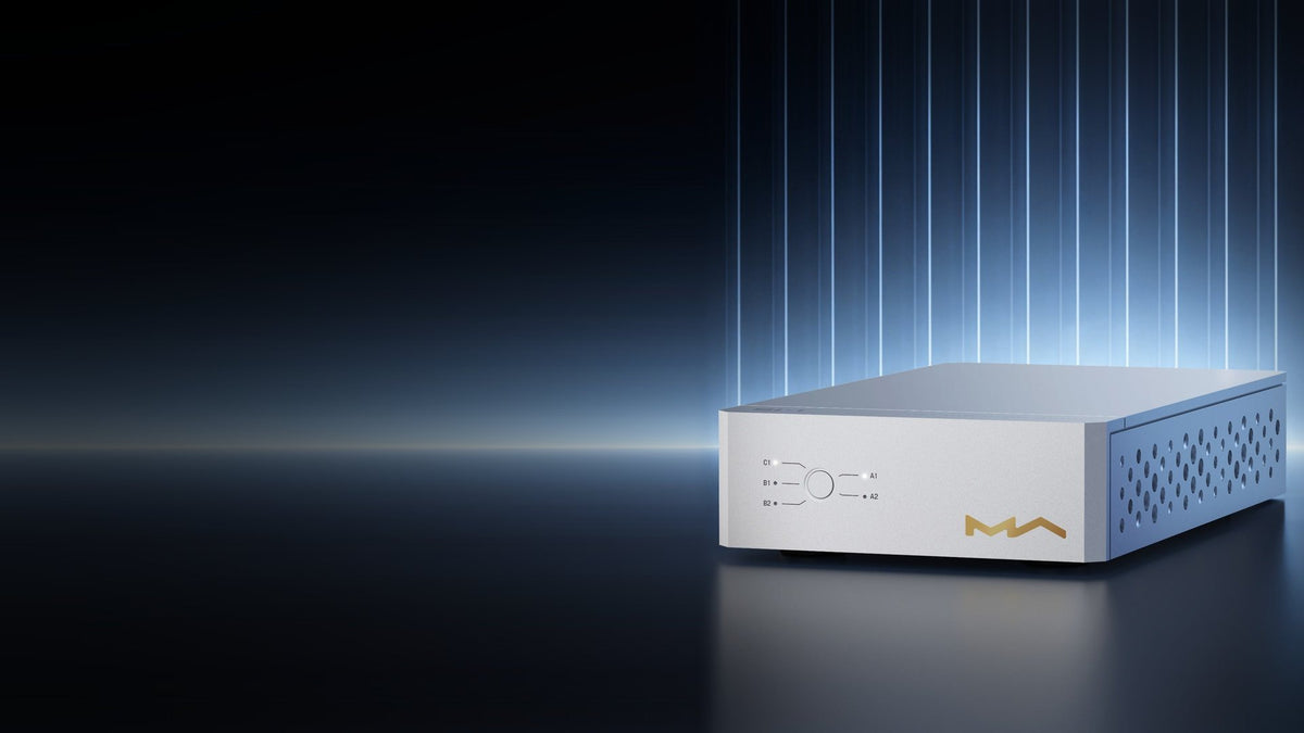 Matrix Audio SU-1 USB isolation switcher in silver on a dark stage with blue light bars
