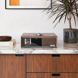Ruark Audio R610 Music Console in Walnut, lifestyle on marble countertop with plant