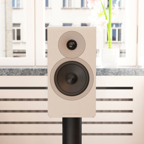Acoustic Energy AE300² in silk-touch matte white on a stand in a modern living room, grille removed to show the drivers