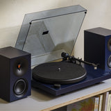 Cambridge Audio Spira Belt Drive Turntable, Blue, lifestyle, on a shelf between matching Blue L/R active speakers