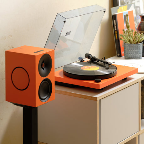 Cambridge Audio Spira Belt Drive Turntable, Orange, lifestyle, on a shelf unit beside a matching Orange L/R active speaker