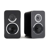 Rega Kyte bookshelf speakers in black, pair with one facing front and one angled, showing the ZRR tweeter and chrome-ringed bass driver