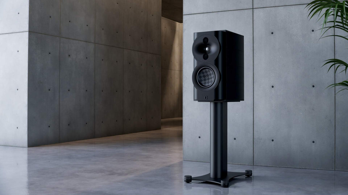 Perlisten S4b Black Edition bookshelf speaker on a stand in a concrete hall
