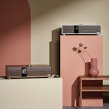 Ruark Audio R410 All-In-One Music System lifestyle showing Walnut and Satin Charcoal finishes in coral set design