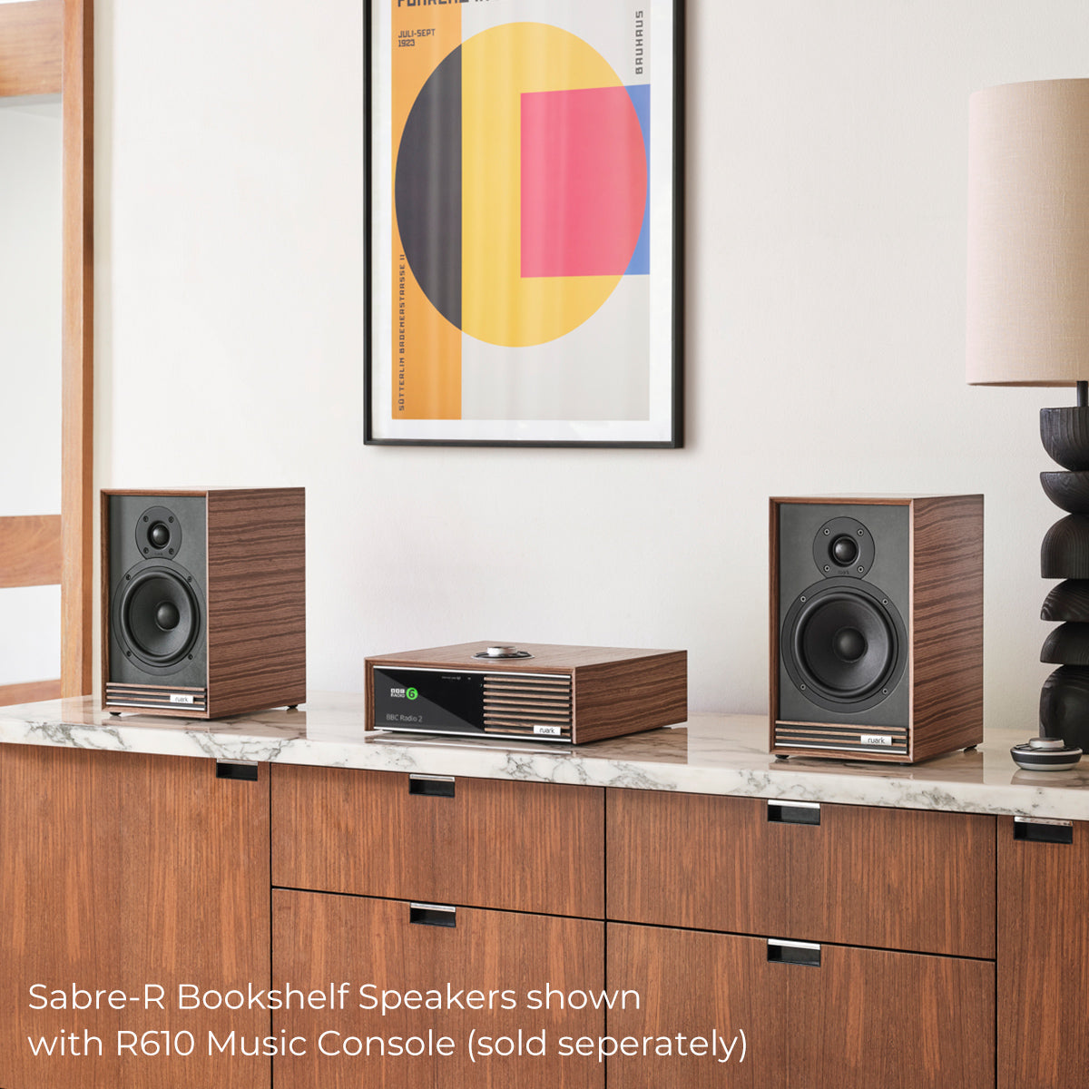 Ruark Audio Sabre-R Bookshelf Speakers in Walnut, lifestyle with R610 Music Console and Bauhaus poster (sold separately)