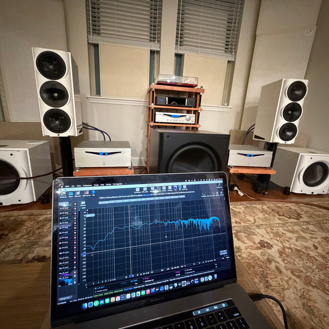Two-channel system calibration in a listening room: REW measurement on Mike's laptop in front of the speakers and three subwoofers