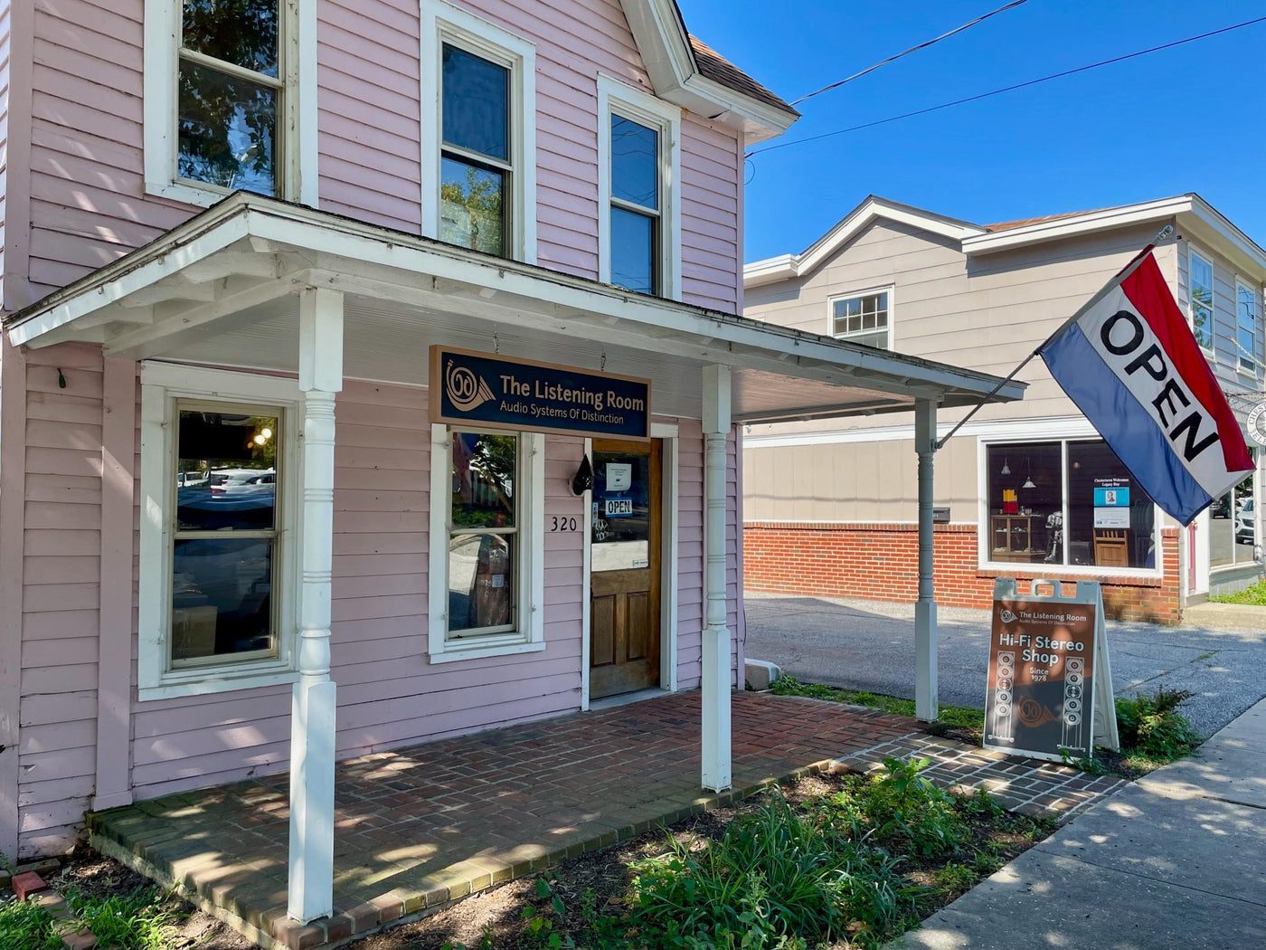 The Listening Room storefront at 320 Cannon Street in Chestertown, Maryland, a pink two-story building with a covered porch and an Open flag.